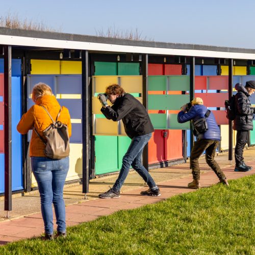 Photographers taking photos of colourful Southsea beach huts