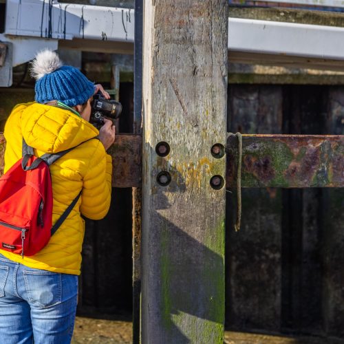 Photographer looking with their camera along a rusty girder